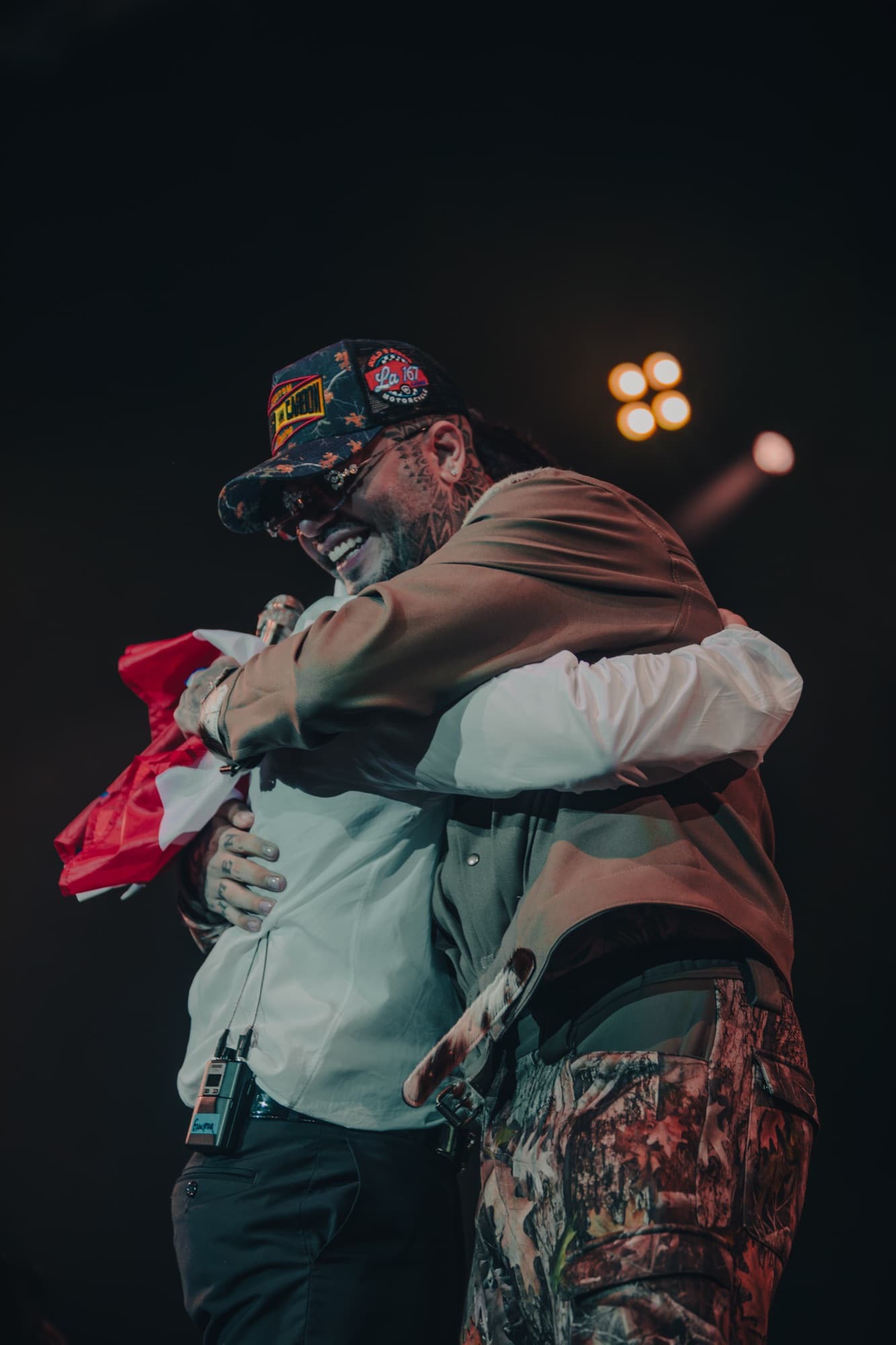 Artists hugging wrapped in the Puerto Rican flag