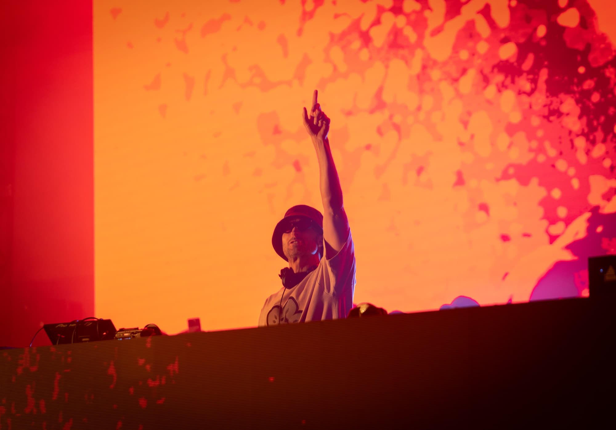 DJ pointing skyward against a wall of orange confetti