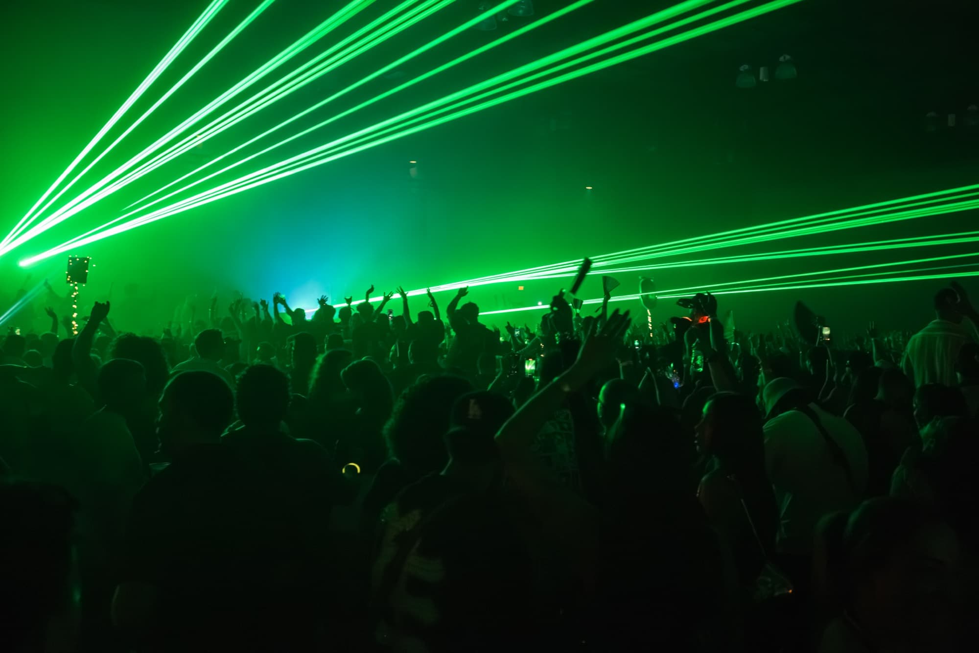 Green lasers sweeping over a packed dancing crowd