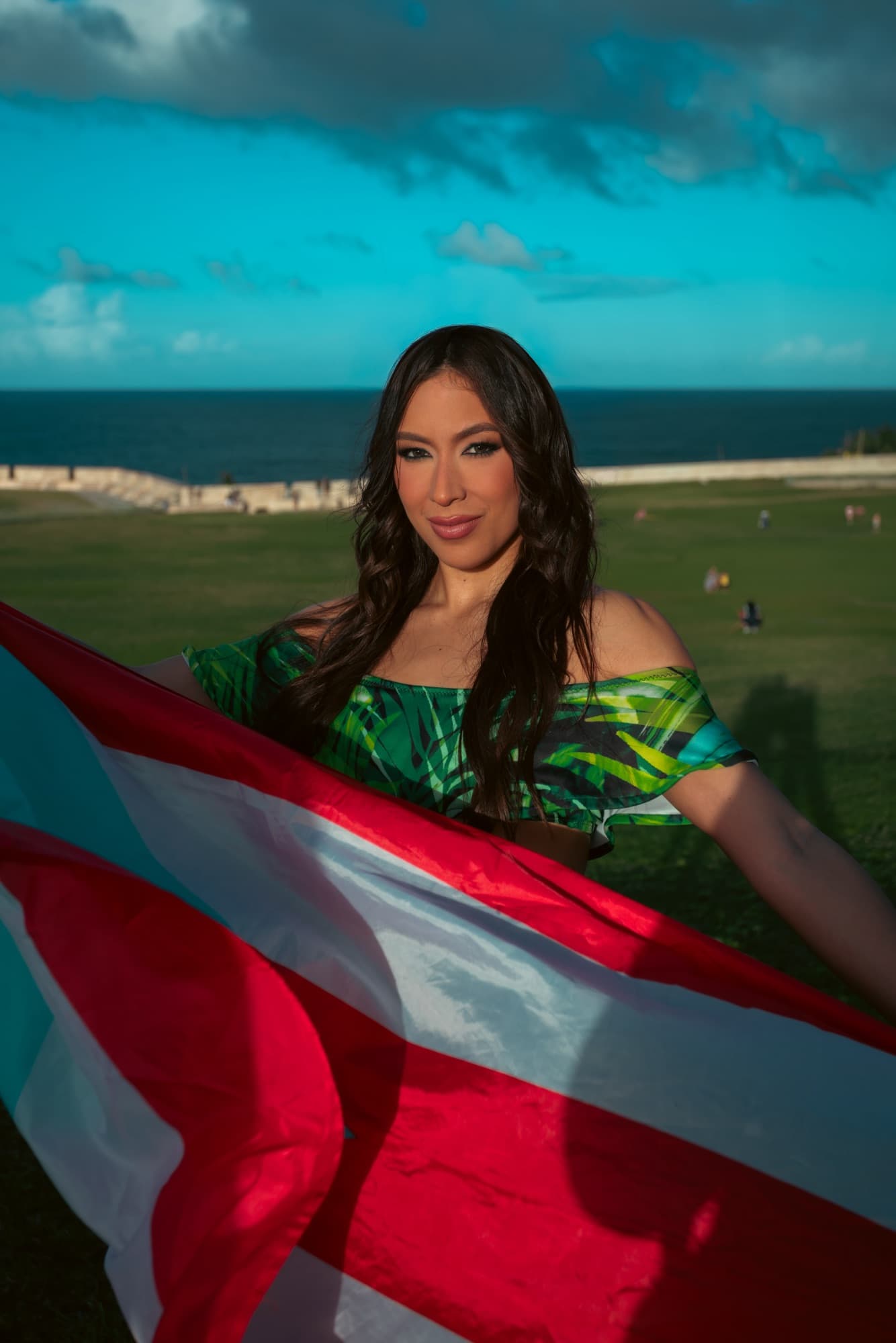 Woman holding the Puerto Rican flag with the Atlantic behind her