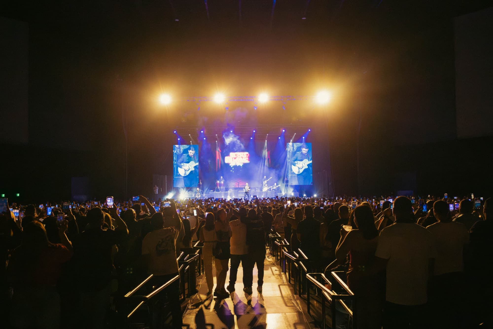 Concert crowd silhouetted under warm amber stage lights